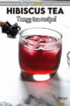 Red hibiscus tea served in a glass wth ice cubes.