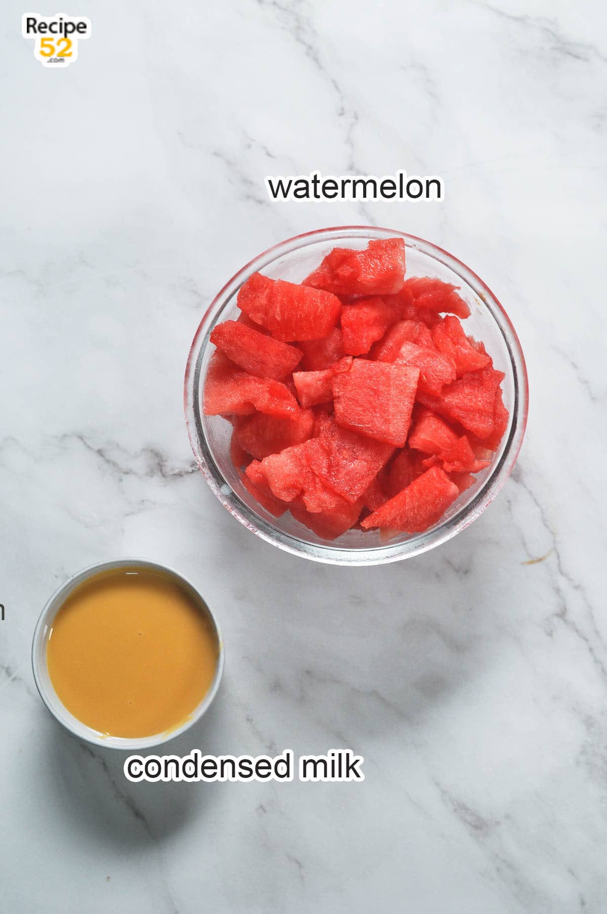 Watermelon cubes in a glass bowl and condensed milk in a container.