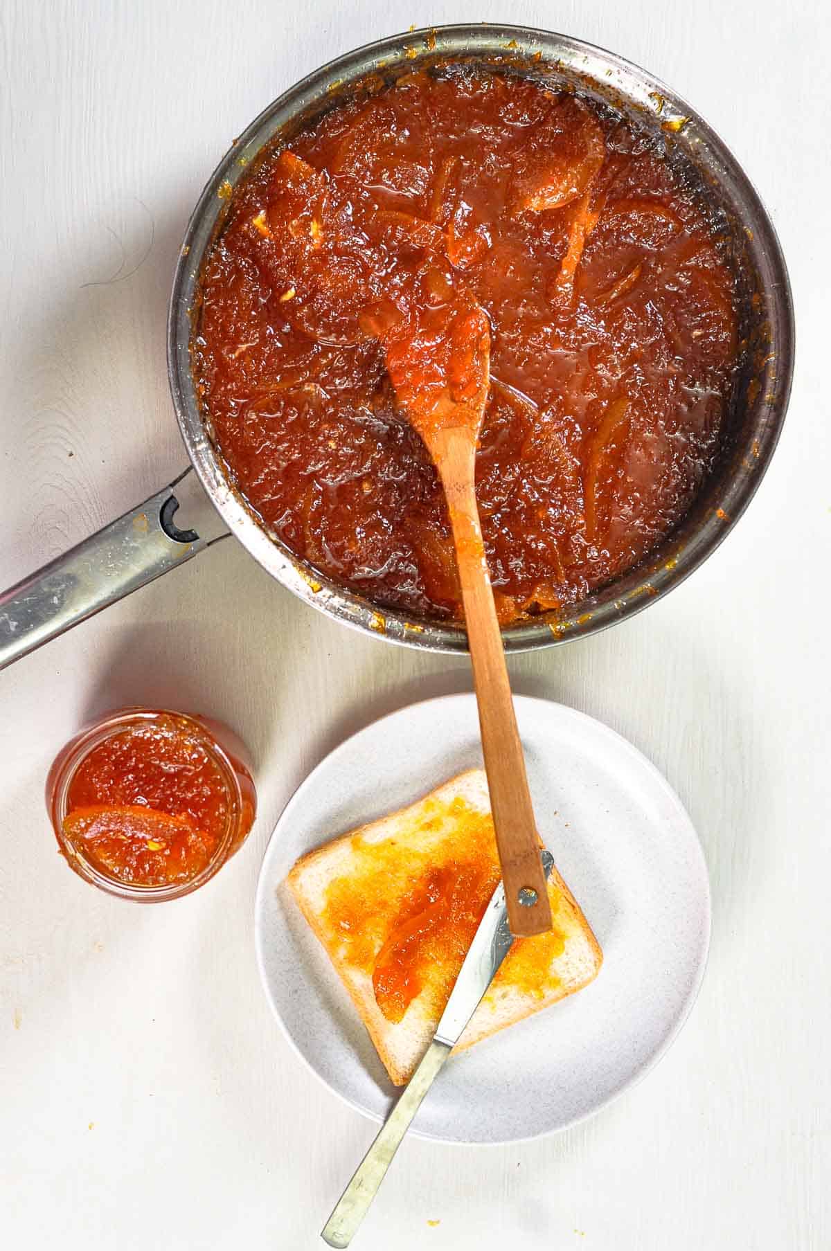 Grapefruit jam in a pan, in a jar, and lathered on a piece of bread. - 3