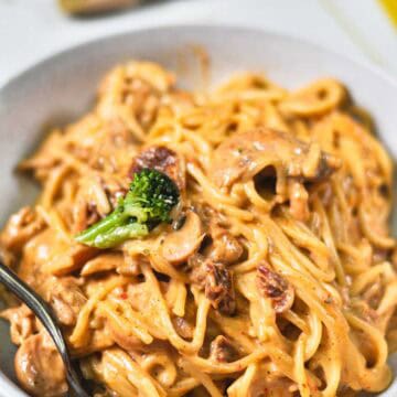 Creamy saucy spaghetti in a white ceramic bowl.
