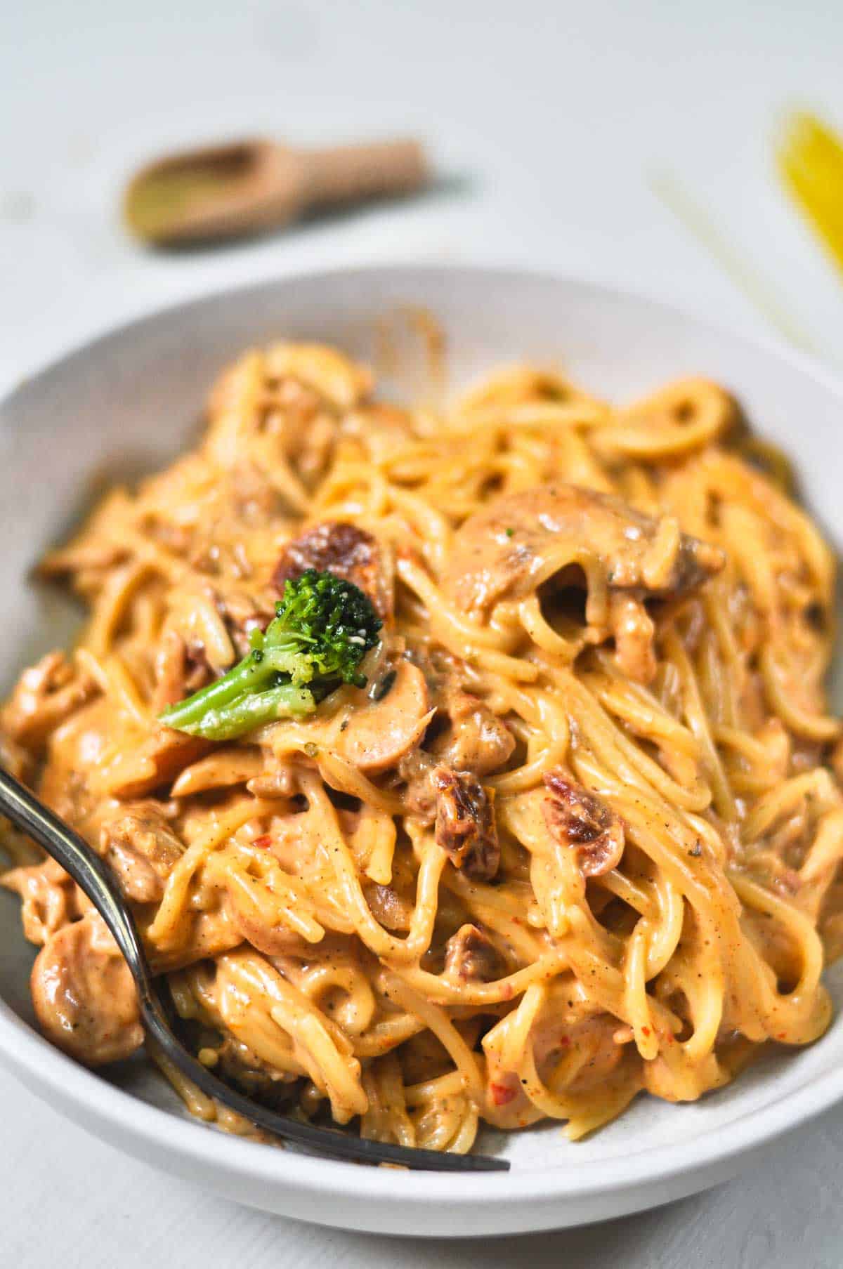 Creamy saucy spaghetti in a white ceramic bowl.