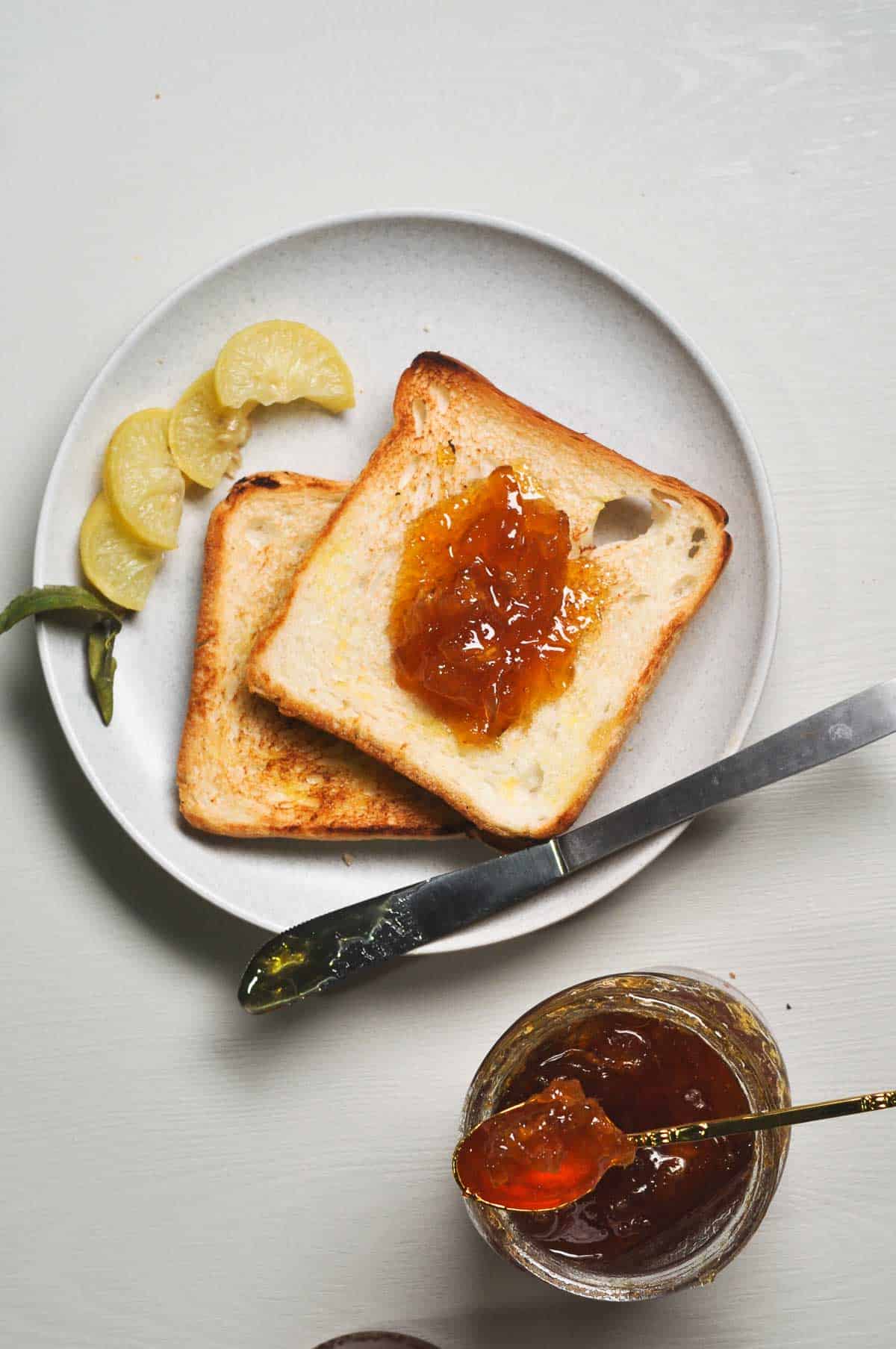 Slices of bread on a plate  with jam slathered on it.