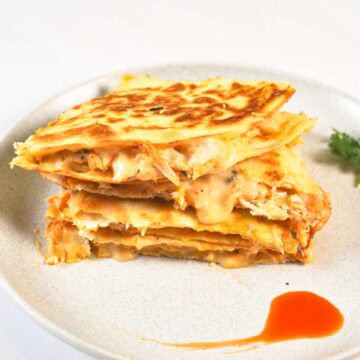 Close up image of quesadilla with splash of buffalo sauce.